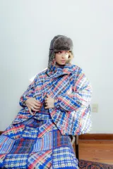 Campera puffer con estampado a cuadros en tonos azul, rojo, amarillo y blanco. Diseño capitoneado a mano y forro interior verde. Corte holgado. Ideal para usar con un look casual.