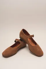 Zapato estilo Mary Jane color marrón, de cuero, con punta redondeada y tira sobre el empeine con hebilla.