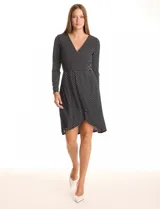 Vestido de seda fría marca Luxology, color negro con estampado de lunares blancos. Presenta escote en V cruzado, cintura elastizada con apliques metálicos, manga larga y ruedo con corte asimétrico.