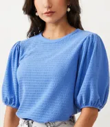 Blusa de punto texturizado color celeste, con cuello redondo y mangas cortas abullonadas.