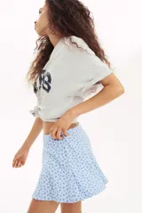 Short pollera mini de tejido suave con efecto neopreno, color celeste con estampado floral en azul oscuro. Modelo ajustado con elástico oculto en la cintura y nesgas que aportan volumen.