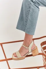 Sandalias de tacón color beige con puntera cuadrada, tiras doradas en el empeine y tobillo, y taco cuadrado.