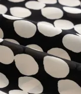 Blusa de crepé satinado con estampado de lunares, escote en V cruzado y mangas cortas tipo campana.