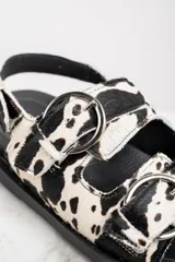 Sandalias con plataforma de goma negra y tiras de pelo de vaca con hebillas plateadas.
