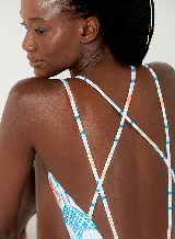 Traje de baño enterizo blanco con estampado de figuras geométricas en tonos celeste, naranja y verde. Tiene escote en V, breteles finos dobles y espalda cavada.