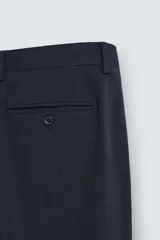 Pantalón de vestir azul marino, de corte slim fit, confeccionado en tejido con 17% de lana. Cuenta con bolsillos frontales y traseros de doble vivo con botón. Cierre frontal con cremallera y botón.