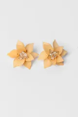 Par de caravanas con forma de flor color durazno y centro con apliques de strass.