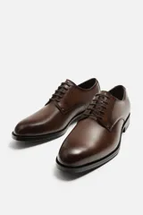 Zapato de vestir marrón tipo derby, con parte superior lisa, horma en punta y suela con ligero tacón.