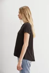 Remera negra de mangas cortas y calce holgado, confeccionada en algodón peruano. Presenta largo irregular y ruedo redondeado.