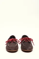 Mocasín tipo boat shoe con estampado de vaca en tonos marrón y blanco, confeccionado en cuero. Cuenta con cordones de cuero marrón oscuro y suela de goma.