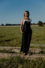 Conjunto de top y pantalón negro. El top es blanco en la parte superior y negro en la parte inferior, con un bordado en el frente. El pantalón es de corte recto ancho, con bolsillos a los costados y cintura con botones y elástico.