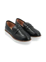 Mocasín de cuero negro con perforaciones decorativas y suela blanca de plataforma.