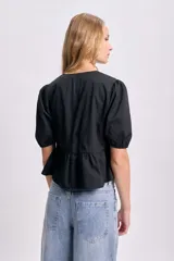 Blusa negra con escote redondo y mangas cortas abullonadas. Presenta lazos frontales para ajustar el escote y un corte con frunce en la cintura.