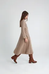 Vestido midi de punto color visón con cuello redondo y mangas largas acampanadas.
