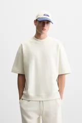 Sudadera negra de corte relaxed fit, confeccionada en tejido interlock de algodón con elasticidad. Tiene cuello redondo, manga corta y bajo acabado en rib.