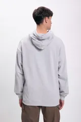 Canguro deportivo gris claro con capucha y bolsillo tipo canguro. Estampado frontal con la frase "Uncovering revealing hidden truths" y un pequeño logo.