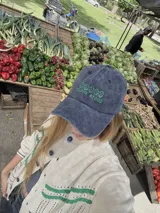 Gorra de gabardina azul con visera curva y bordado frontal en verde con la leyenda "Costa Dulce".