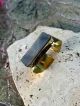 Pulsera rígida dorada con piedra rectangular gris veteada.
