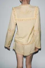 Shorts color crema de tiro alto con cintura elástica, bordados florales y puntilla a tono.