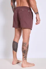 Short de baño color marrón con cordón ajustable en la cintura y logo estampado en blanco en la pierna izquierda.