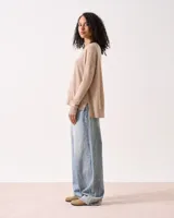 Sweater de tejido de punto color beige claro, con cuello redondo, manga larga y sisa caída. Presenta un detalle de costura vertical central en el frente y terminaciones acanaladas en puños y ruedo.