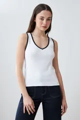 Musculosa de punto canalé color beige con cuello en V y ribete blanco en contraste.