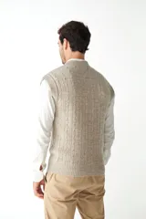 Chaleco de punto color beige con diseño de trenzas, escote en V y sisas amplias.