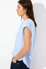 Blusa celeste a rayas verticales blancas, de corte holgado, manga corta y cuello mao con escote en V.
