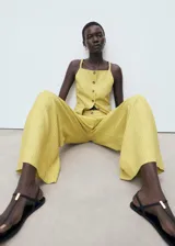 Pantalón de tiro alto, diseño recto y largo, color amarillo claro con finas rayas verticales. Presenta cierre de botón y cremallera, detalle de pinzas y dos bolsillos laterales.