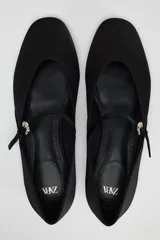 Zapato tipo bailarina color negro con efecto satinado, punta redonda y tira con hebilla ajustable.