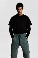 Pantalón jogger deportivo color verde grisáceo, con cintura elástica ajustable con cordón, bolsillos laterales con cierre, bolsillos cargo con solapa y bajos elásticos.