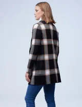 Cardigan tejido de mujer, color negro con diseño de cuadros grandes en blanco y beige/tostado. Presenta cuello con solapa y abertura frontal con botones, y bolsillos aplicados.