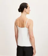 Blusa blanca de viscosa con breteles finos y escote en pico.