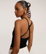 Body negro de tejido acanalado, con escote redondo y tirantes finos que se cruzan en la espalda.