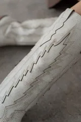 Bota de cuero color marrón con bordado decorativo en el caño, taco bajo y punta fina.