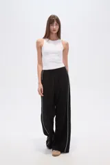 Pantalón deportivo negro de corte ancho y tiro alto, con cintura elástica y cordón ajustable. Presenta una raya blanca vertical a cada lado.