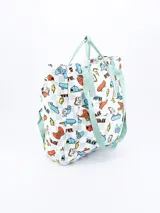 Mochila blanca con estampado de videojuegos, patinetas, gafas de sol y otros motivos. Tiene asas de mano y tirantes de color verde agua.