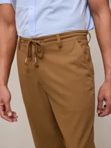 Pantalón de vestir color beige, de corte recto, con bolsillos laterales y traseros. Se ajusta a la cintura con cordón.