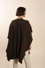 Ruana color crema tejida en punto fantasía con efecto de volado en los bordes.