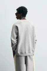 Sudadera gris de tejido compacto con mezcla de algodón y viscosa, corte relaxed fit, cuello redondo con rib combinado a contraste, manga larga y acabados en rib.