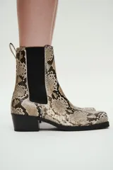 Botas Chelsea de mujer con estampado de piel de serpiente en tonos beige, negro y marrón. Presentan punta y taco cuadrados, elásticos laterales negros y una trabilla trasera para facilitar el calce.