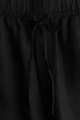 Pantalón tobillero negro de corte holgado en tejido liviano de mezcla de lino. Modelo de tiro alto con elástico revestido y cordón para ajustar fino en la cintura, bolsillos al bies y piernas ajustadas.