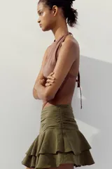 Falda pantalón corta color verde oliva, de tiro medio con detalle de pliegues en la cintura y volantes en el ruedo.