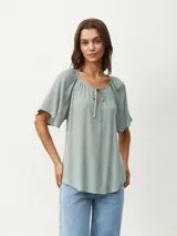 Blusa blanca de mangas cortas con escote redondo y lazos.