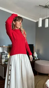 Sweater rojo de tejido de punto trenzado con cuello alto y mangas largas.