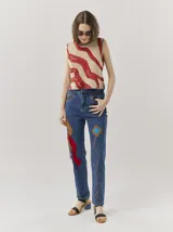 Pantalón de jean azul con parches de colores, tiro alto, corte mom-fit, apliques de cuero trenzado alrededor de los bolsillos frontales y canutillos en la parte frontal.