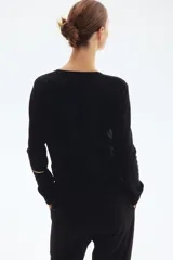 Saco de punto negro con cuello redondo y botones dorados. Tiene remate acanalado en cuello, puños y bajo.