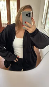 Campera negra oversize de tela tipo plush con cierre frontal y capucha.
