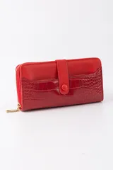 Billetera roja con cierre de cremallera y detalle de solapa con botón a presión. La parte inferior tiene un diseño texturizado que simula piel de cocodrilo.