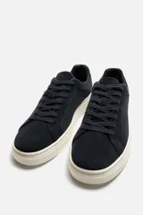 Zapatillas de hombre con cordones, fabricadas en piel serraje color azul marino. Suela plana color hueso y horma redonda.